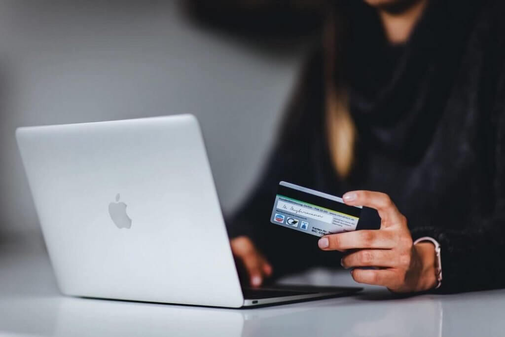 a woman using her macbook while holds her card